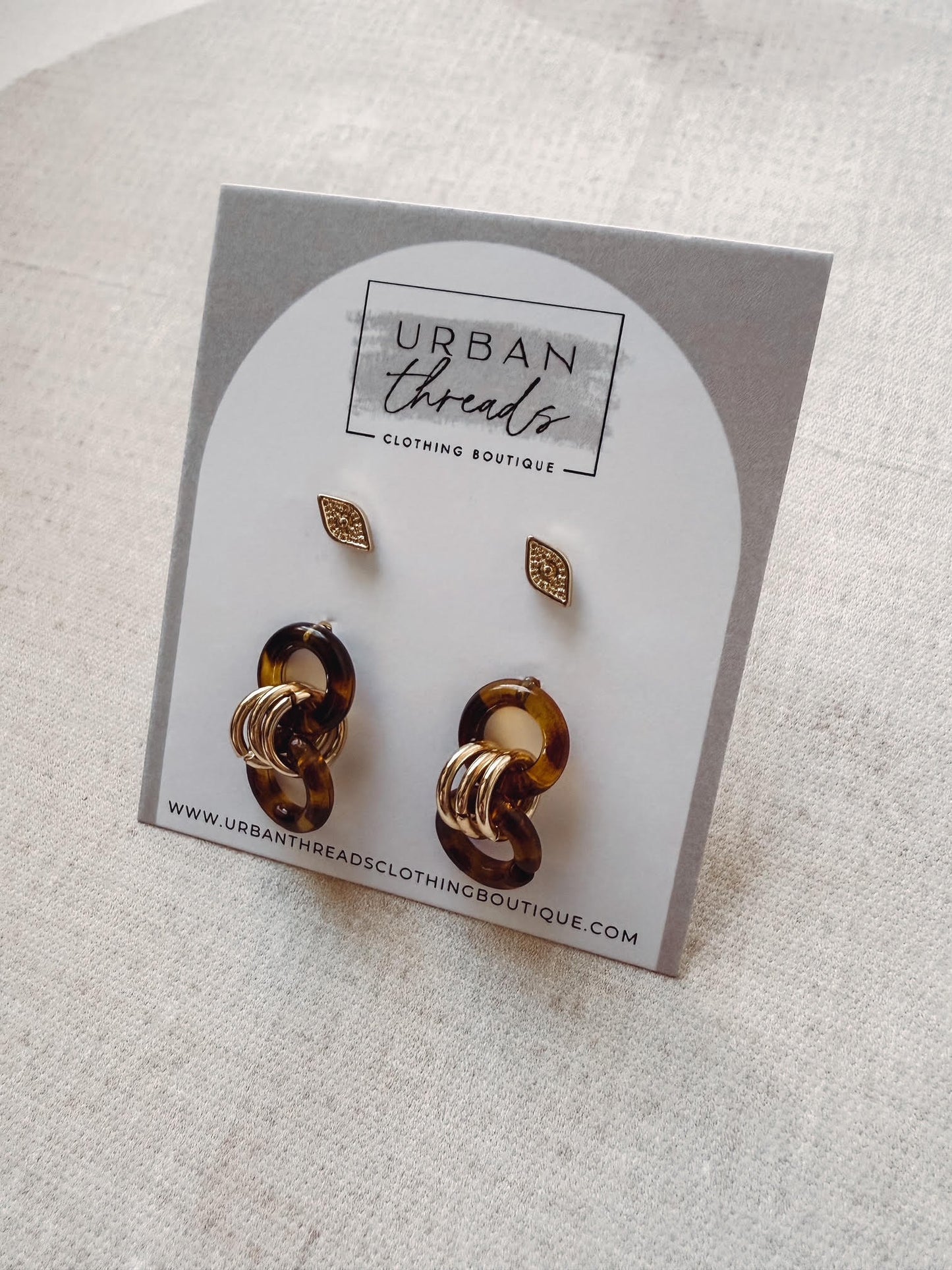 Pair of gold and brown earrings on a 'Urban Threads' branded card.