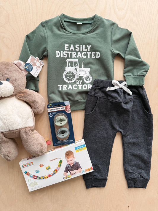Children's outfit with green shirt, gray pants, and toys on a wooden surface