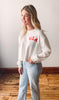 Woman wearing a white shirt with 'USA' text standing indoors.