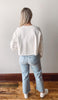 Person wearing a white shirt and light blue jeans from the back.