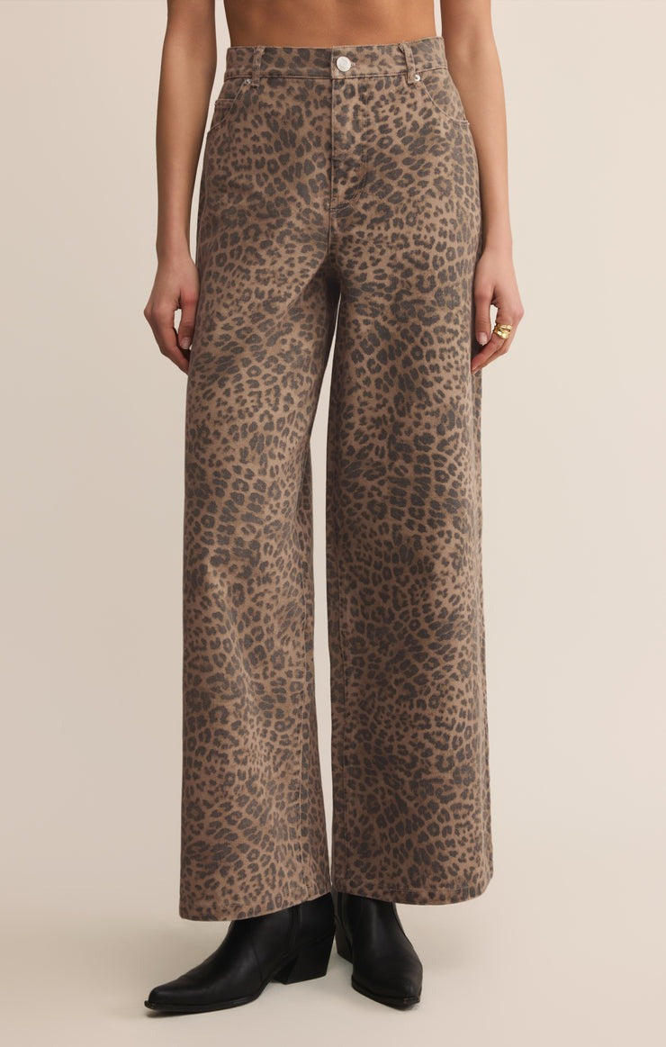 Leopard print pants worn by a person on a beige background