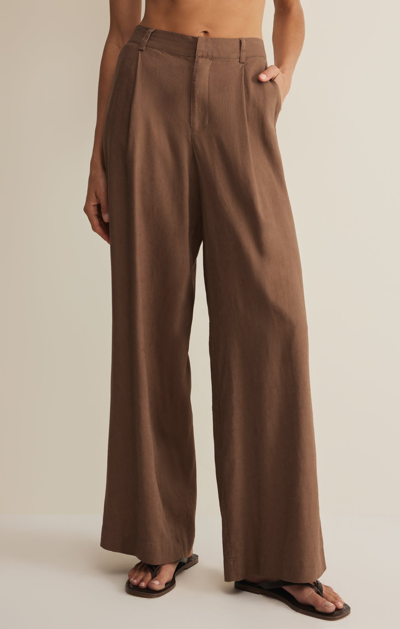 Brown wide-leg pants worn by a person on a beige background