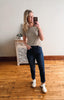 Woman taking a mirror selfie wearing a beige t-shirt and blue jeans in a room with wooden flooring.