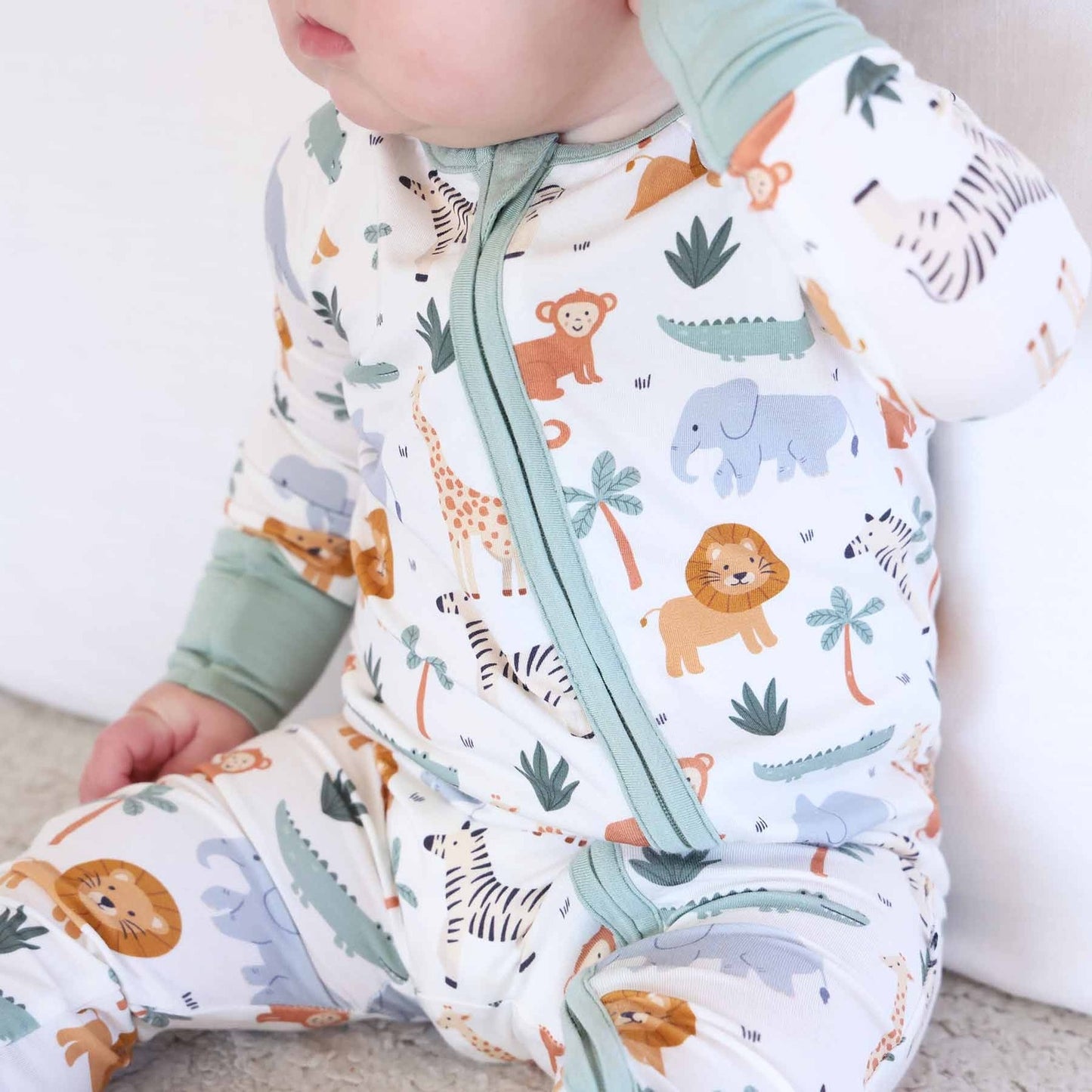 Baby wearing a sleep bag with animal print on a neutral background