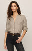 Woman wearing a checkered shirt and black pants against a plain background