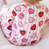 Heart-patterned baby romper with text on a striped background