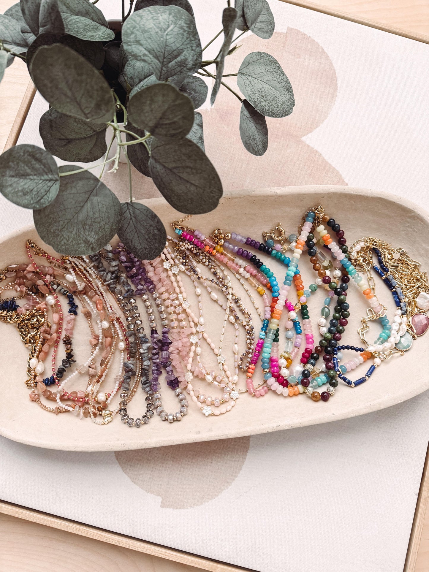 Colorful beaded bracelets on a white dish with green leaves