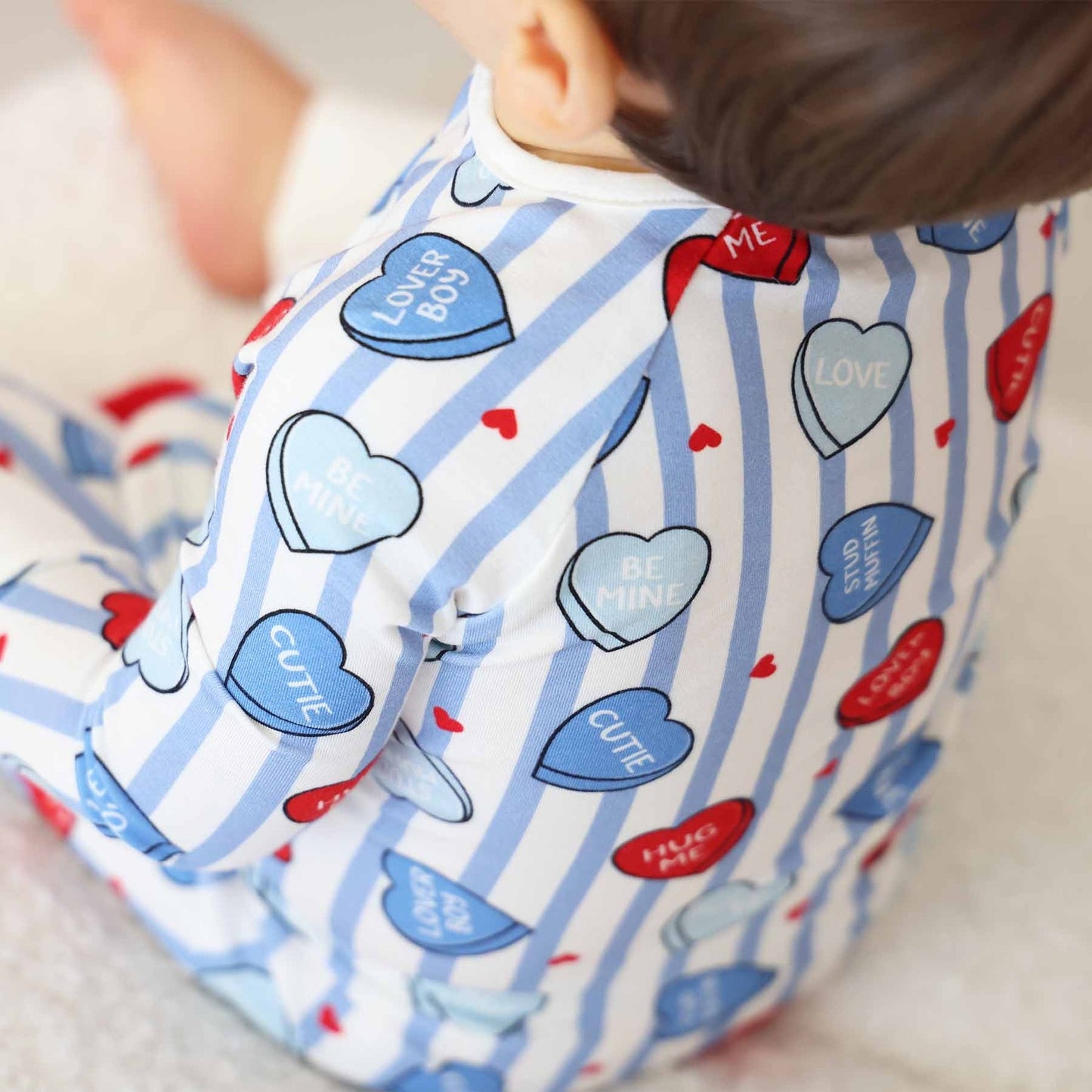 Baby wearing a onesie with heart-shaped text and stripes