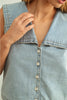 Light blue denim shirt with buttons being buttoned up, close-up.