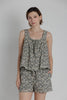 Woman wearing a floral sleeveless top and shorts set on a plain background