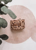 Leopard print product on a pink circular background with green leaves