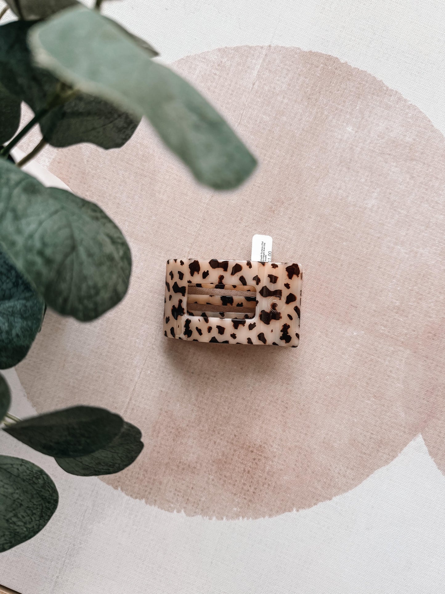 Leopard print product on a textured surface with green leaves