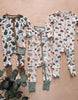 Three baby onesies with different patterns on a wooden surface.