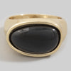 Gold ring with a black stone on a light gray background