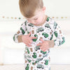 Child wearing a pajama set with green truck pattern on a white background