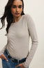 Woman wearing a gray long-sleeve top and blue jeans against a white background