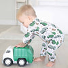 Child playing with a toy garbage truck wearing pajamas with vehicle patterns.
