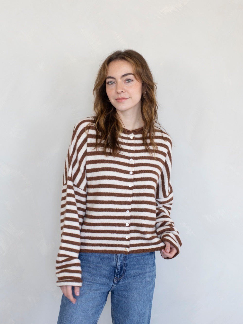 Woman wearing a brown and white striped sweater against a plain background