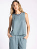 Woman wearing a light blue sleeveless top and pants on a white background