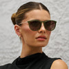 Woman wearing green sunglasses against a textured gray background
