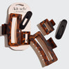 A Kit & Sch recycled plastic assorted claw clip set, featuring three brown tortoiseshell hair clips and two matte black clips, with one set displayed on its original packaging and the other set arranged flat on a light gray background.