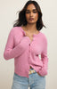 Woman wearing a pink cardigan and light blue jeans against a plain background