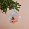 Decorative ornament with 'kit-sch' branding hanging on a Christmas tree branch.