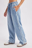 Light blue wide-leg denim jeans with white side stripes, worn by a model with white and brown sneakers against a light gray studio background.