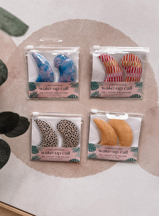 Four pairs of wake-up call eye masks in different designs on a textured surface.