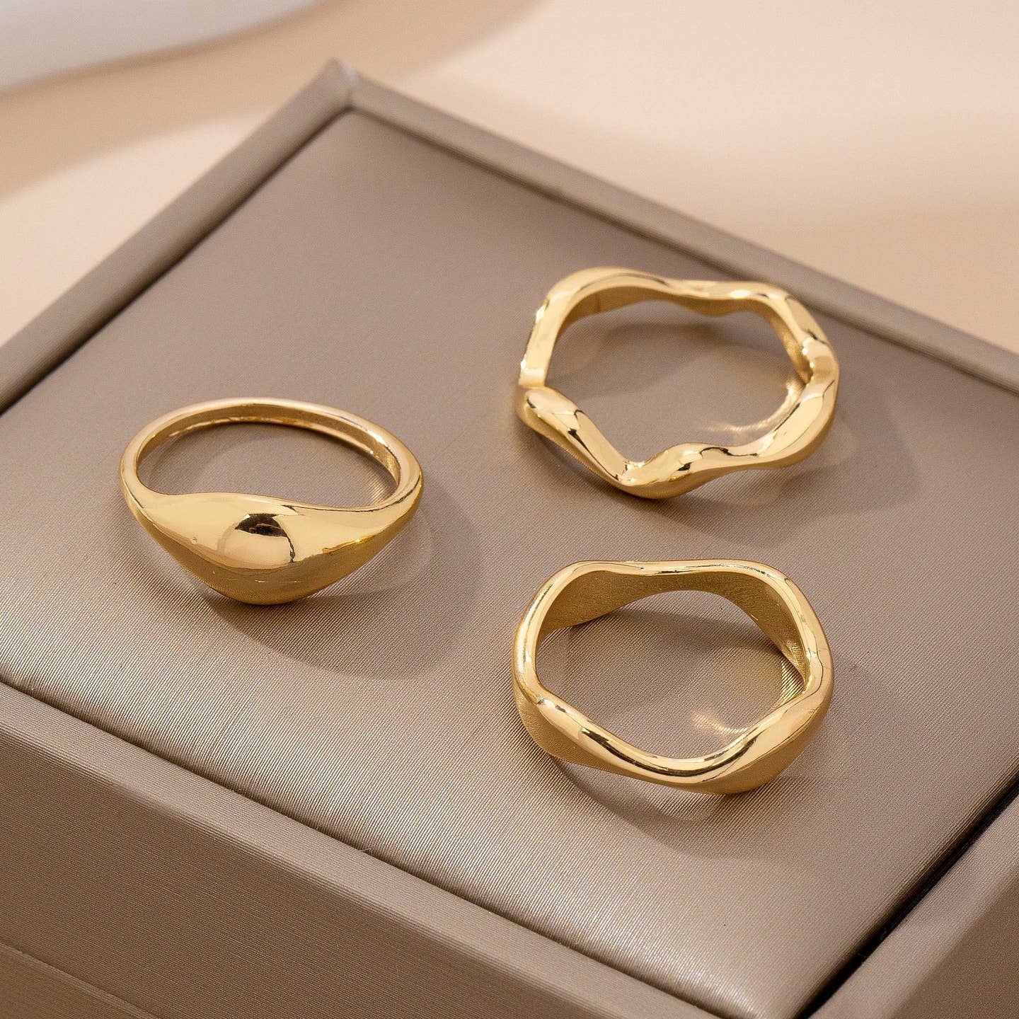 Three gold rings on a beige textured surface