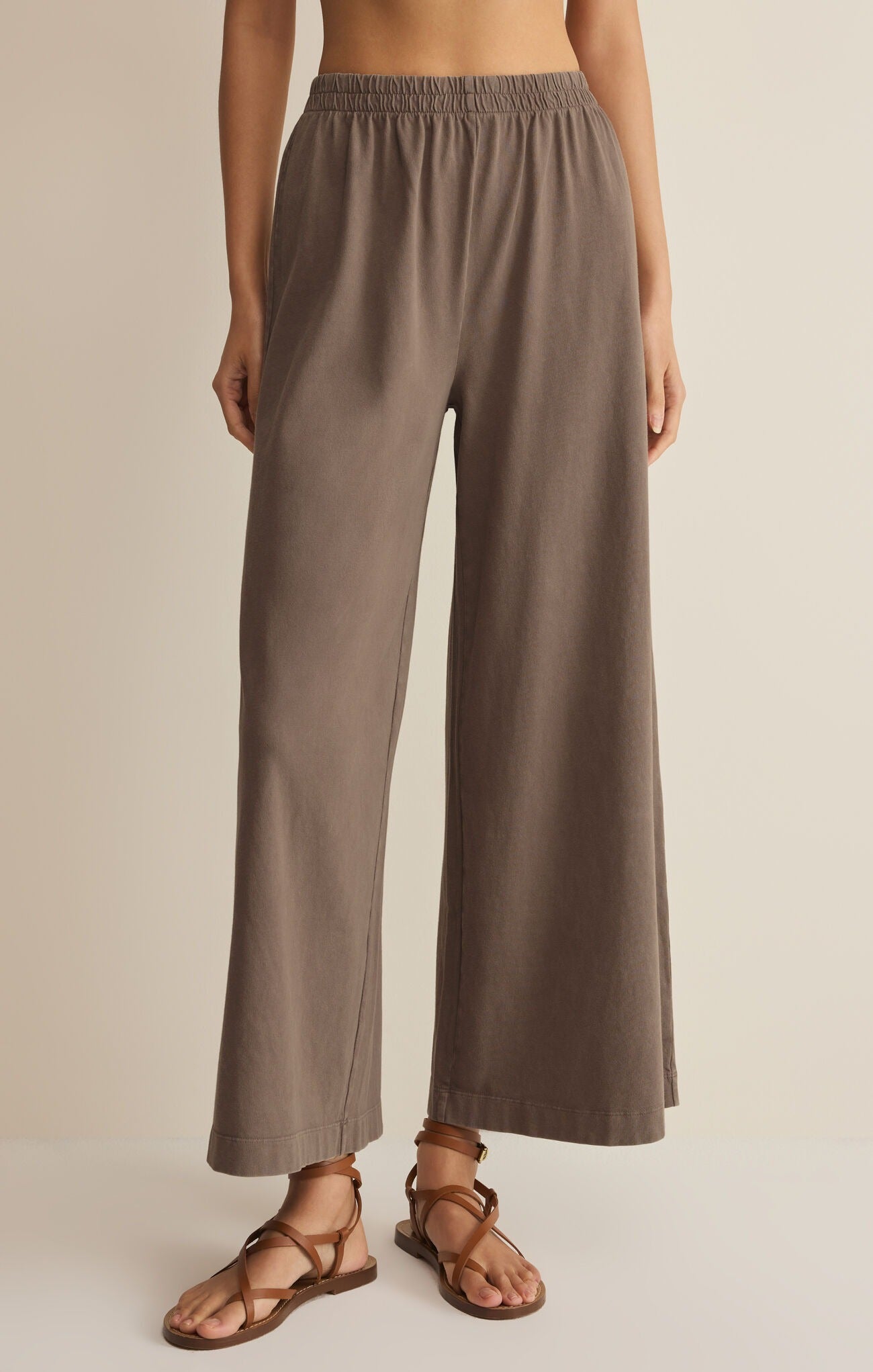 Brown wide-leg pants worn by a person on a beige background