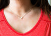 Person wearing a red shirt and gold necklace with a heart pendant