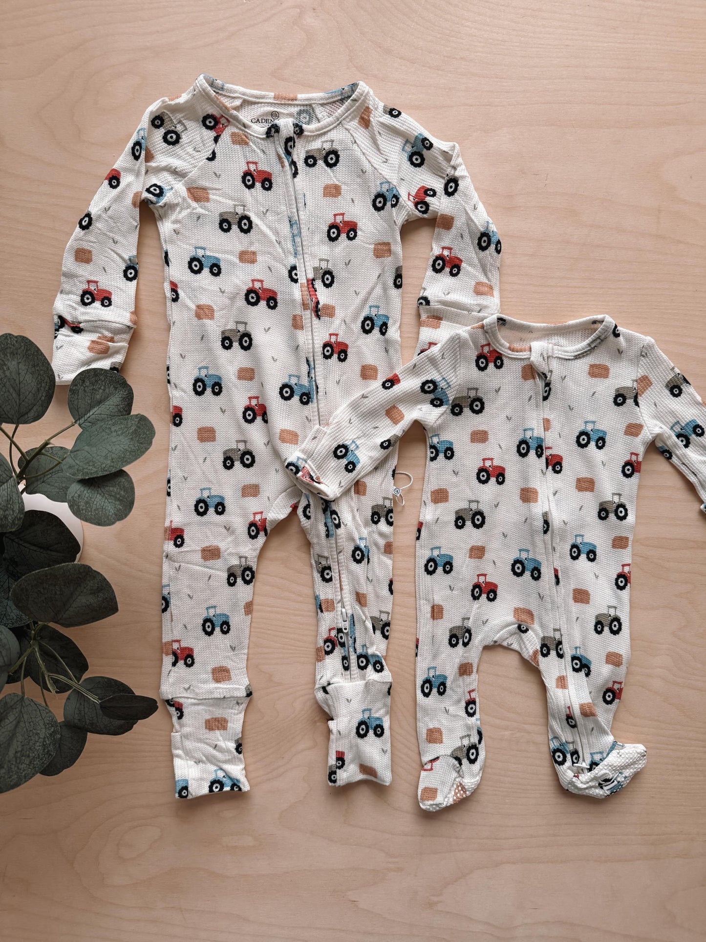 Two baby rompers with truck pattern on a wooden surface