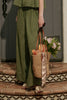Person holding a woven bag with bread and flowers on a patterned step.