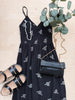 Navy blue dress with white floral patterns, sandals, and a clutch on a beige surface.