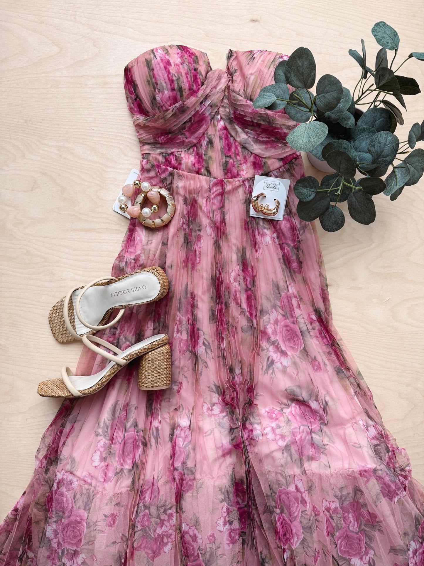 Pink floral dress with sandals and a plant on a beige surface