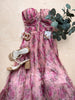 Pink floral dress with sandals and a plant on a beige surface