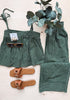 Green and white striped swimsuit with sunglasses and sandals on a light background