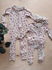 Two baby onesies with floral pattern on a wooden surface.