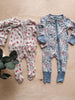 Two baby rompers with floral patterns on a wooden surface.