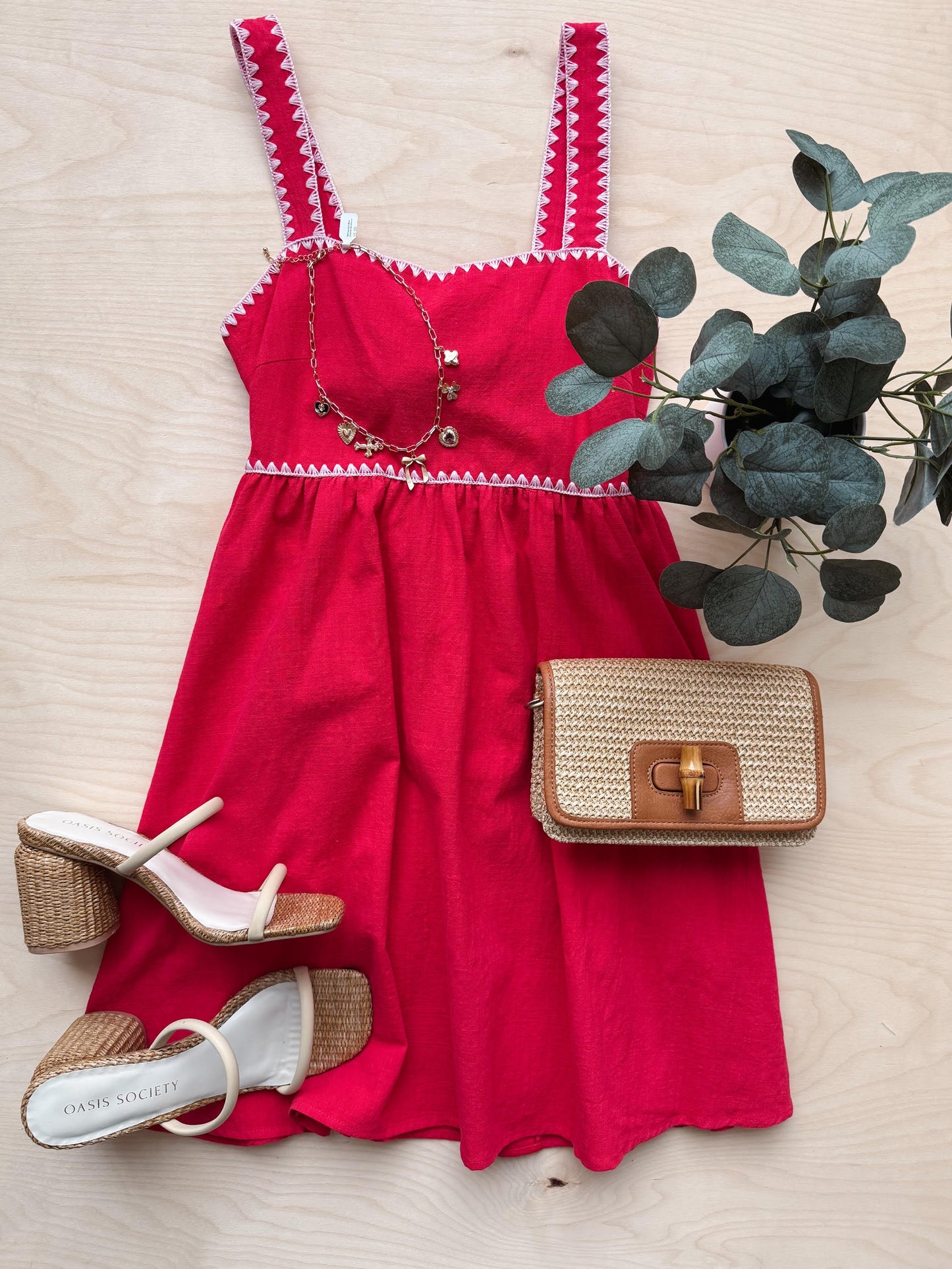 Red dress with matching sandals and a handbag on a wooden surface