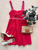 Red dress with matching sandals and a handbag on a wooden surface