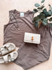 Brown tank top and shorts set with a white sandal, clutch, and necklace on a light wooden surface.