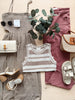 Collection of clothing and accessories including a dress, tank top, pants, shoes, and handbags on a neutral background.