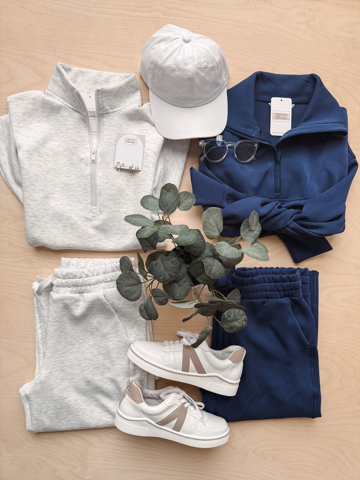 Gray and navy clothing items with white sneakers on a wooden surface