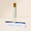 Roll-on bottle of 'night swim' with gold cap on a beige background