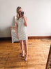 Woman taking a mirror selfie wearing a striped dress in a room with wooden flooring.