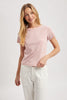 Woman wearing a pink and white striped t-shirt and white pants on a light gray background
