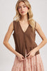 Woman wearing a brown sleeveless top with a plain background