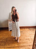 Woman taking a mirror selfie wearing a brown top and floral skirt on a wooden floor.